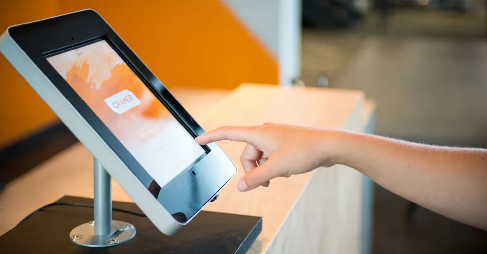 An Envoy visitor sign-in tablet on a stand at a reception desk (image: envoy.com)